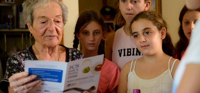 Older woman reading a brochure as young girls read behind her