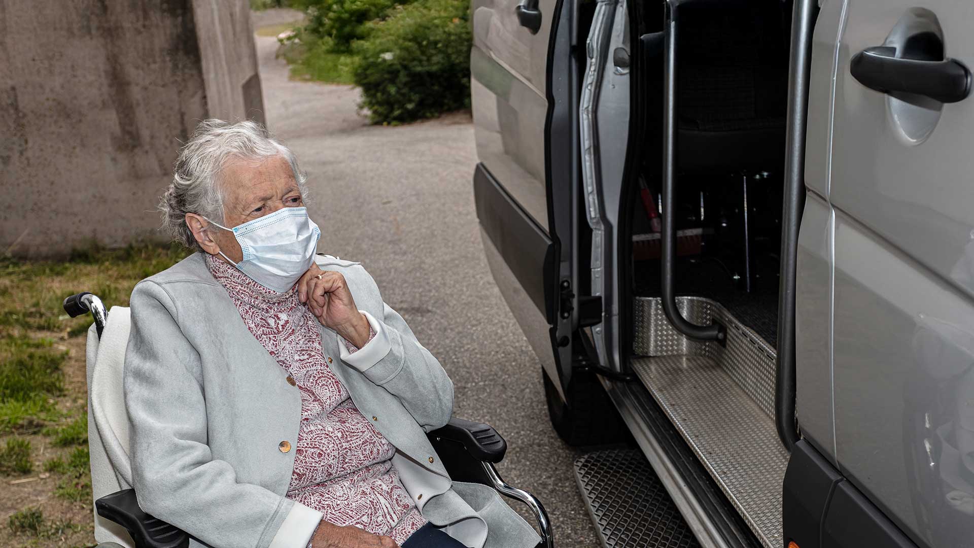 elderly woman in wheelchair waiting for help into a van