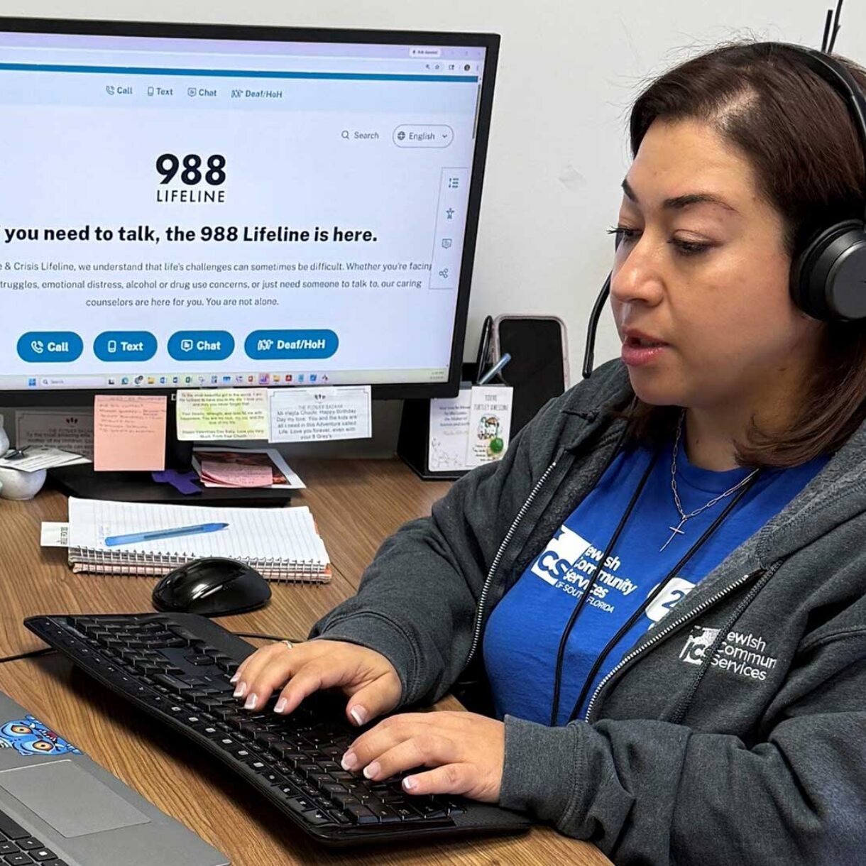 a woman sits at a call center desk fielding calls for the 988 suicide and crisis lifeline